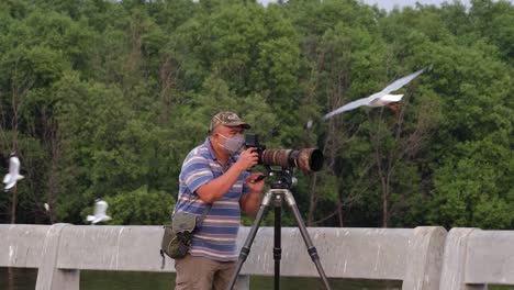 A-man-moves-towards-his-camera-with-his-mask-on-as-he-takes-photographs-of-Seagulls-flying-around-in-Bang-Pu-Recreation-Center,-Thailand