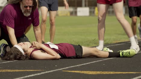 colapsed-runner-on-track-recieves-help-from-teammate-and-coach-on-a-hot-summer-day