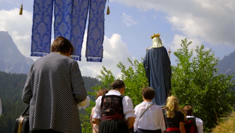 Una-Pancarta-Y-Una-Estatua-De-La-Virgen-María-Son-Llevadas-Por-Mujeres-Vestidas-Con-Trajes-Tradicionales-Tiroleses-Durante-Una-Procesión-Católica.