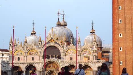 Venice---Saint-Mark's-Square-with-Campanile,-tourists-walking-in-the-foreground-and-pigeons-flying-above