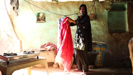 Young-Indian-girl-hanging-clothes-at-home,-Noondpura-Muslim-village-in-Rajasthan