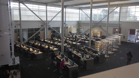 top-view-of-college-students-walking-around-in-a-library-working-on-computers