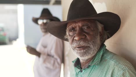 Aboriginal-man-gazing-into-camera-while-a-truck-passes-in-outback-Australia