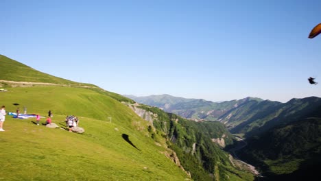 Gleitschirmfliegen-über-Dem-Tal-Mit-Leuten,-Die-Auf-Kazbegi-Zusehen