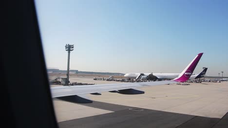 Pista-De-Rodaje-Asfaltada-Del-Aeropuerto-De-Frankfurt-Con-Equipo-De-Avión,-Toma-Pov-Desde-La-Ventana-Del-Avión-Con-Ala-En-Primer-Plano