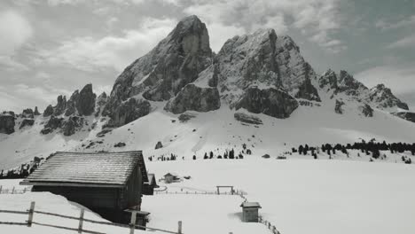 Flying-past-some-wooden-huts-with-a-massive-mountain-as-background