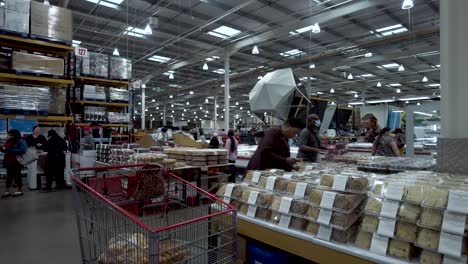 Shopper-Picking-Up-Pastry-Selection-Box-And-Putting-It-In-Trolley-At-Costco-On-28-May-2022