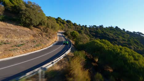 FPV-aerial-following-a-green-Lamborghini-driving-along-a-scenic-country-highway-in-Spain