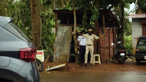 Oficial-De-Policía-Indio-Observa-El-Tráfico-Apoyado-En-Un-árbol-Hablando-Con-Un-Residente-Local