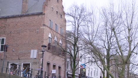 Clip-Panorámico-A-Lo-Largo-Del-Canal-En-Utrecht-Desde-Un-Barco,-Desde-Edificios-Y-Tiendas-Hasta-El-Agua-Y-Un-Puente