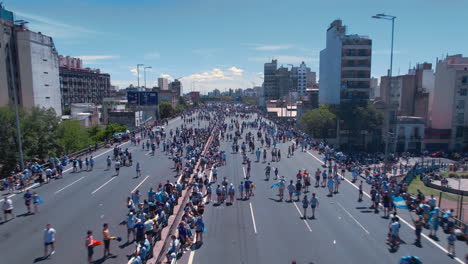 Aerial-shot-of-highway-crowded-with-football-soccer-argentinian-fans-during-world-cup-celebration,-parade-and-gather-around-on-a-sunny-day