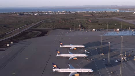 Flyover-grounded-fleet-from-Icelandair-lined-up-on-tarmac-during-sunset,-aerial