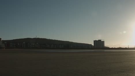 Sunrise-Slow-Panning-Shot-of-Beach-front-with-Kilvey-HIll-in-Swansea-UK-4K