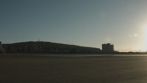 Toma-Panorámica-Lenta-Del-Amanecer-Frente-A-La-Playa-Con-Kilvey-Hill-En-Swansea,-Reino-Unido-4k