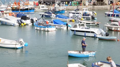 Ein-Mann-Paddelt-Ein-Kleines-Boot-Im-Hafen-Von-Lyme-Regis-Inmitten-Einer-Masse-Von-Booten