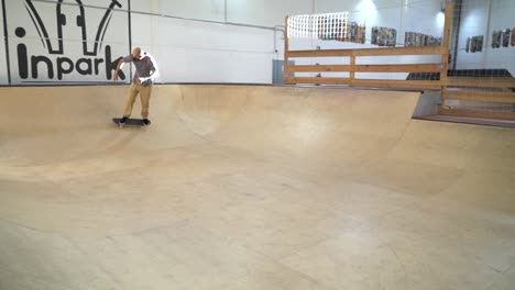 Professional-skater-with-skinhead-and-protective-mask-driving-in-skateboard-park-during-covid19-pandemic