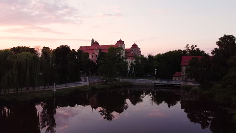 Rising-over-still-water-reflecting-clouds-to-look-from-above-at-castle-in-Niemodlin