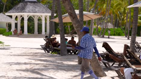 Tropical-resort-worker-serving-drinks-and-walking-on-beach