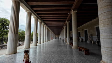 Child-runs-joyfully-near-the-ancient-colonnade,-the-timeless-columns-standing-tall-as-witnesses-to-history