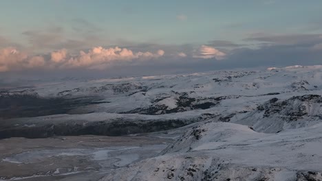 Aerial-footage-of-the-snow-covered-mountains-in-Myrdalur,-Iceland,-during-dusk,-highlighting-the-serene-and-pristine-landscape