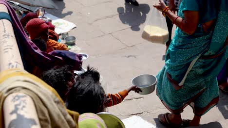 Mujeres-Indias-Donando-Alimentos-A-Personas-Pobres-De-La-Calle-Durante-El-Día.-Video-Tomado-En-Dashashwamedh-Ghat-Varanasi-Uttar-Pradesh,-India,-08-De-Marzo-De-2024.