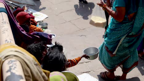 Indische-Frauen-Spenden-Lebensmittel-An-Arme-Obdachlose,-Tagsüber-Video-Aufgenommen-Am-Dashashwamedh-Ghat-Varanasi-Uttar-Pradesh-Indien,-08.-März-2024