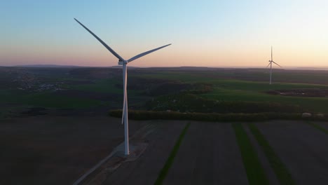 Wind-turbine-stands-tall-in-a-vast-landscape-during-sunset,-harnessing-renewable-energy