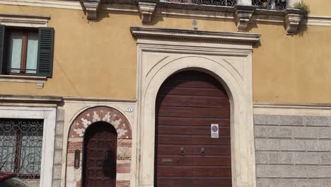 Casa-Típica-De-La-Ciudad-Italiana-Con-Puertas-De-Madera-Y-Un-Balcón-Con-Esculturas,-Verona