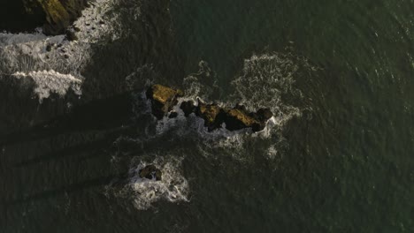 Stunning-aerial-footage-of-the-Reynisdrangar-basalt-sea-stacks-off-the-coast-of-Vik,-Iceland,-showcasing-the-dramatic-rock-formations-amidst-the-waves-of-the-North-Atlantic-Ocean