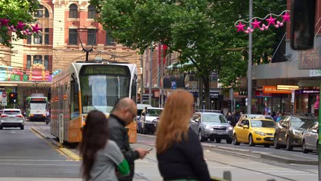 The-bustling-city-of-Melbourne,-trams-running-along-Elizabeth-Street,-slow-vehicles-traffic,-and-street-decorated-with-festive-decorations-during-the-Christmas-season,-a-vibrant-urban-street-scene