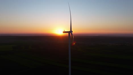 Wind-turbine-spinning-at-sunrise-over-a-vast-landscape