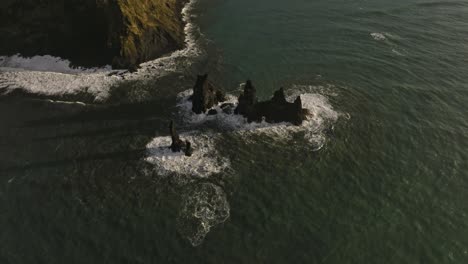 Aerial-footage-capturing-the-iconic-Reynisdrangar-sea-stacks-and-the-rugged-cliffs-along-the-coastline-of-Vik,-Iceland,-showcasing-the-natural-beauty-and-dramatic-landscape