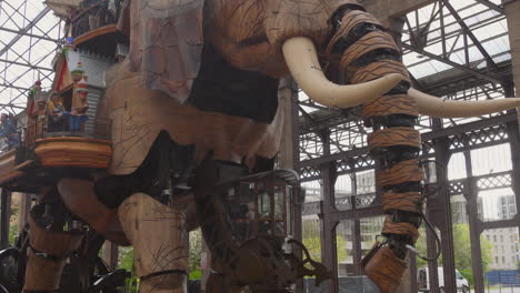 Tilt-down-shot-of-The-Great-Elephant-machine-in-the-Isle-of-Nantes,-carrying-passengers-in-city-square-in-Nantes,-France-at-daytime