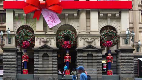 El-Ayuntamiento-De-Melbourne-Decorado-Con-Adornos-Navideños-Durante-La-Temporada-Festiva,-Con-Tranvías-Que-Se-Deslizan-Por-La-Escena-A-Lo-Largo-De-Swanston-Street,-Mostrando-El-Vibrante-Ambiente-Festivo-De-La-Ciudad.