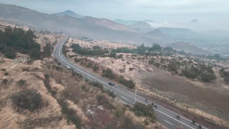 cyclists-pedaling-at-high-speed-over-the-top-of-a-hill-in-the-municipality-of-Barnechea,-Chile