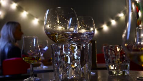 Imágenes-En-Movimiento-Lento-De-Una-Degustación-De-Ginebra-De-Copas-De-Ginebra-Llenas-De-Ginebra-Y-Bebidas-En-Un-Acogedor-Bar-Oscuro-Con-Luces-Satisfactorias-De-Fondo-En-4k-En-Tallin,-Estonia,-Europa