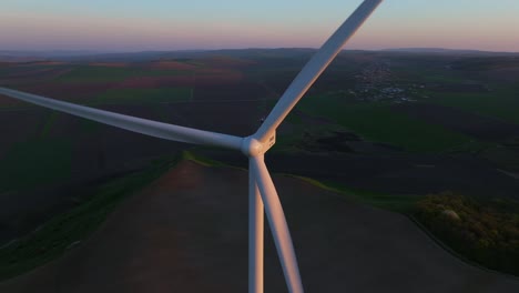 Wind-turbine-spinning-in-a-vast-countryside-during-sunset,-aerial-view