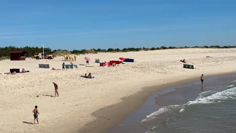 La-Gente-Toma-El-Sol-Y-Juega-A-La-Pelota-En-El-Lugar-Tranquilo-De-La-Playa-De-Furadouro-En-Ovar,-Portugal.