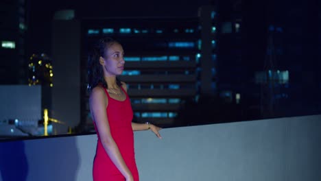 A-rooftop-with-a-Hispanic-girl-and-the-Caribbean-city-lights-of-Port-of-Spain,-Trinidad-in-the-background