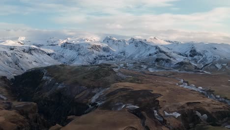 Atemberaubende-Luftaufnahmen-Der-Schneebedeckten-Berge-Und-Des-Zerklüfteten-Geländes-In-Myrdalur,-Island,-Unter-Einem-Klaren-Himmel