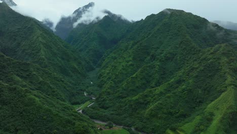 Tahiti-French-Polynesia-Teahupoo-aerial-drone-raining-fog-up-the-mountain-peaks-river-morning-grey-gray-season-wet-green-Point-Faremahora-village-town-South-Pacific-Mount-Tohivea-island-forward-motion