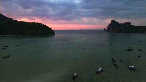 Botes-Tradicionales-Tailandeses-De-Cola-Larga-Flotando-En-Aguas-Tranquilas-Al-Atardecer-Con-Un-Cielo-Espectacular-En-El-Fondo-Bonita-Vista-Aérea-Vuelo-Drone-Descendente