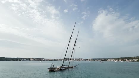 Antique-shipwreck-in-Greek-bay-and-small-sailboats-in-quiet-Mediterranean-marina