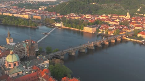 Aerial-view-of-Prague-featuring-the-Charles-Bridge-over-the-Vltava-River,-Old-Town,-and-Lesser-Town-with-historic-architectures-and-lush-greenery