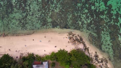 Bunte-Boote,-Die-An-Einem-Tropischen-Inselstrand-Vor-Anker-Liegen,-Mit-Touristen,-Die-Auf-Dem-Weißen-Sand-Spazieren