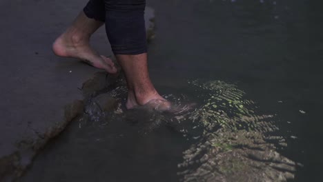 Close-up-of-a-man's-legs-walking-through-cold-water,-capturing-the-movement-and-splashes