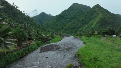 Teahupoo-River-Tahiti-French-Polynesia-aerial-drone-mountains-morning-grey-gray-raining-fog-season-wet-green-grass-end-of-the-road-Point-Faremahora-village-town-buildings-island-backwards-slowly