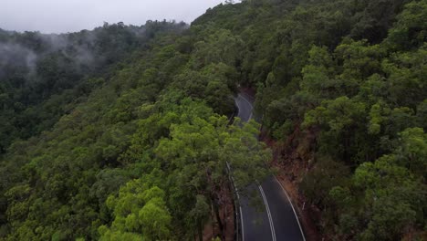 Aerial-View-of-Asphalt-Road-and-Traffic-in-Thick-Humid-Rainforest,-Drone-Shot