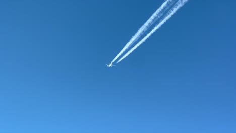 Pilot-POV-of-a-white-color-jet-flying-across-a-blue-sky-with-its-wake-clearly-visible