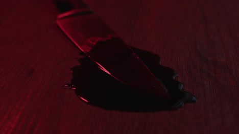 Suspenseful-dolly-of-a-blood-covered-kitchen-knife-in-a-puddle-of-blood-with-flashing-police-lights-in-the-background
